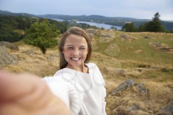 Smiling teenage girl taking a selfie during a mountain hike, close up portrait