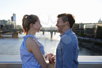 Romantic Couple Standing On Bridge Over River Thames In London