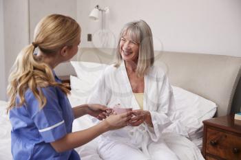 Nurse Making Home Visit To Senior Woman In Bed