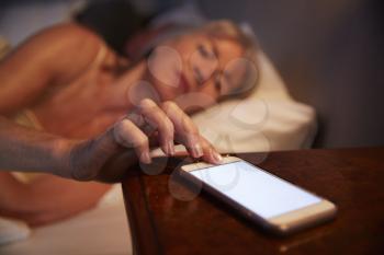 Sleepless Senior Woman In Bed At Night Checking Mobile Phone