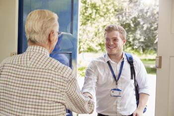 Senior man greeting male care worker making home visit