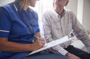 Senior man sits with nurse making notes at retirement home
