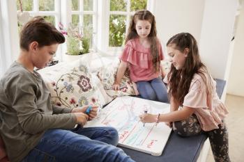 Children Making List Of Chores On Whiteboard At Home