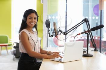 Young mixed race woman recording a podcast smiling to camera