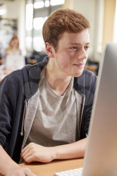 Male Student Working On Computer In College Library
