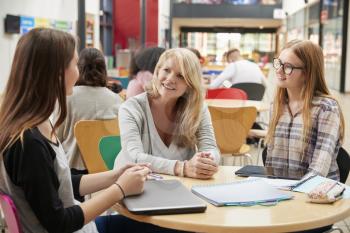 Teacher Talks To Students In Communal Area Of College Campus