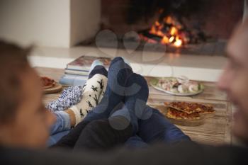 Close Up Of Feet As Family Relax Next To Open Fire