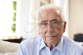 Portrait Of Senior Man Sitting On Sofa Suffering From Depression