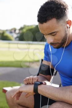 Young male athlete using fitness app on smartwatch, side view