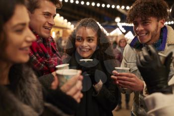 Group Of Friends Drinking Mulled Wine At Christmas Market