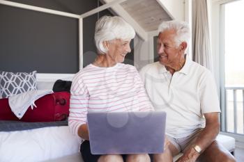 Senior Couple Look At Laptop As They Check In To Vacation Rental