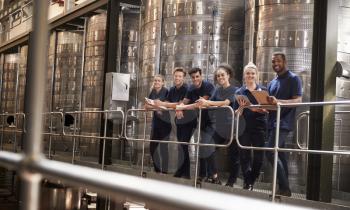 Staff at a wine factory smiling to camera from a gangway