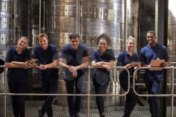 A row of staff at a wine factory smiling to camera, close up
