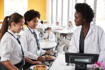 High School Students Wearing Uniform Paying For Meal In Cafeteria