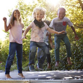 Four kids having fun together on a trampoline in the garden
