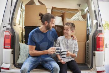 Father And Son Take A Break In Back Of Removal Van On Moving Day