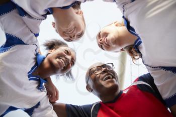 Low Angle View Of Female High School Soccer Players And Coach Having Team Talk