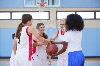 Female High School Basketball Players Joining Hands During Team Talk With Coach