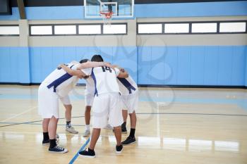 Male High School Basketball Players In Huddle Having Team Talk On Court