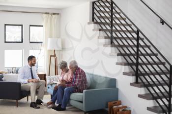 Senior Couple Meeting With Male Financial Advisor At Home