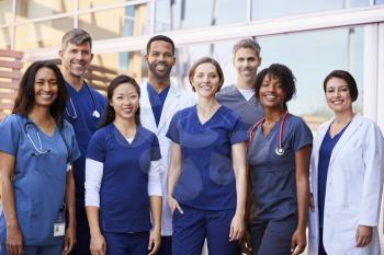 Smiling medical team standing together outside a hospital