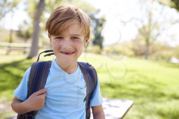 Young white schoolboy with backpack smiling to camera