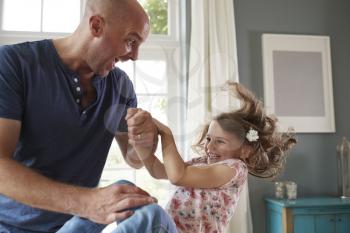 Father and daughter having fun jumping together at home
