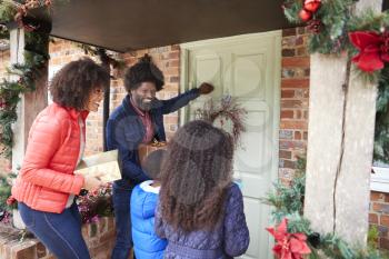 Family Knocking On Front Door As They Arrive For Visit On Christmas Day With Gifts