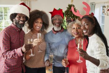 Portrait Of Parents With Adult Offspring Making A Toast With Champagne As They Celebrate Christmas Together