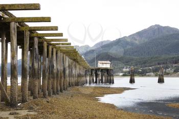 Wooden Jetty Stretching Into Lake With Forest Covered Mountains Behind In Alaska
