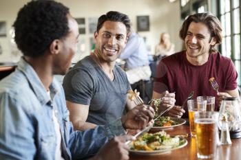 Group Of Male Friends Enjoying Meal In Restaurant Together
