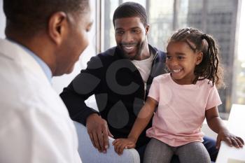 Father And Daughter Having Consultation With Female Pediatrician In Hospital Office