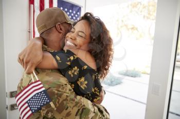 Millennial black soldier embracing his wife after arriving back home,close up