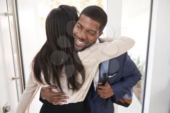 Woman Greeting And Hugging Businessman Husband As He Returns Home From Work