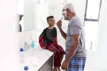 Grandfather Wearing Pajamas In Bathroom Shaving Whilst Grandson Watches