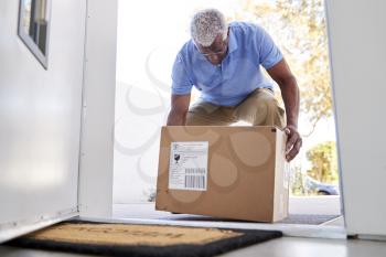 Senior Man Coming Back To Home Delivery In Cardboard Box Outside Front Door