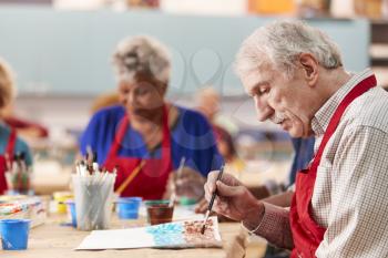 Retired Senior Man Attending Art Class In Community Centre