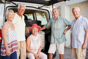 Portrait Of Senior Friends Loading Luggage Into Trunk Of Car About To Leave For Vacation