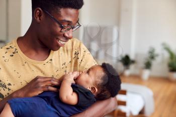 Loving Father Holding Newborn Baby At Home In Loft Apartment