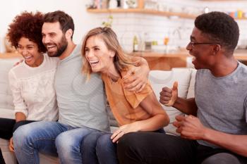 Excited Group Of Friends Sitting On Sofa And Watching Sports On TV