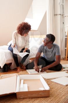 Couple In New Home Putting Together Self Assembly Furniture