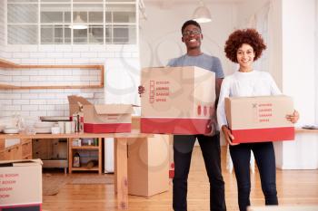 Portrait Of Smiling Couple Carrying Boxes Into New Home On Moving Day