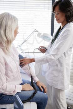 Woman Patient Having Blood Pressure Taken By Female Doctor In Office