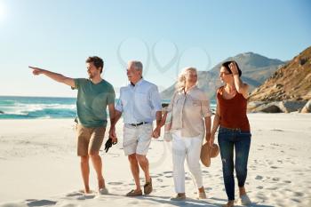 Mid adult and senior white couples walking on a beach together talking, full length, close up