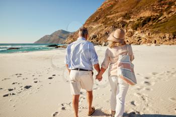 Senior white couple walking on a beach holding hands, back view, three quarter length, close up