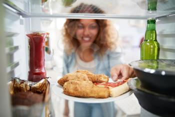 View Looking Out From Inside Of Refrigerator Filled With Takeaway Food As Woman Opens Door