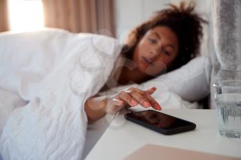 Woman Waking Up In Bed Reaches Out To Turn Off Alarm On Mobile Phone