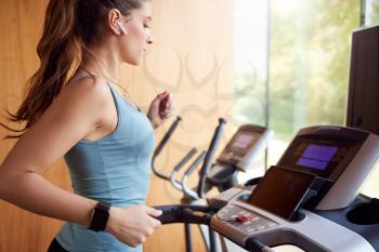 Woman Exercising On Treadmill At Home Wearing Wireless Earphones Checking Smart Watch