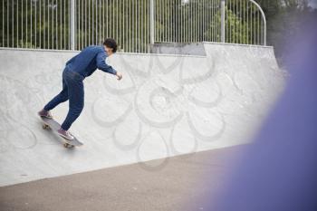 Young Woman Riding On Skateboard In Urban Skate Park