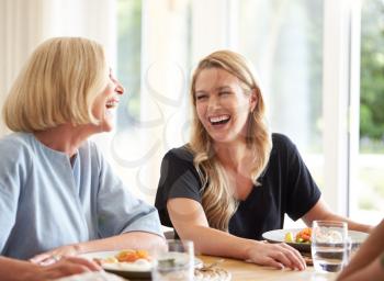 Family With Senior Mother And Adult Daughter Eating Brunch Around Table At Home Together